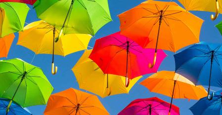 Din forsikring farverige paraplyer foran blå himmel
